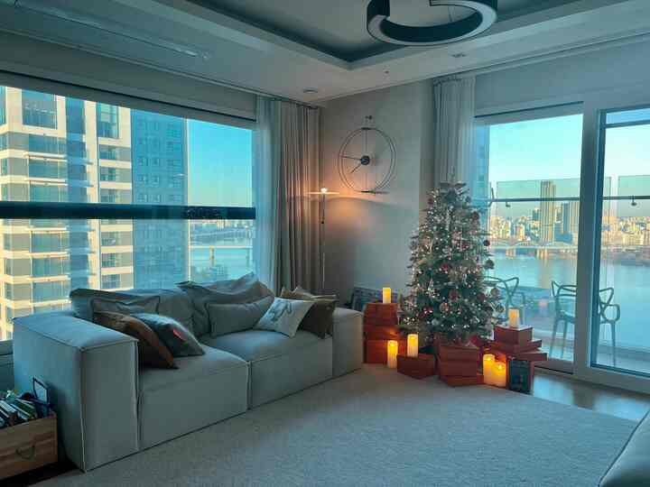 Bright white-toned living room featuring a large sofa and decorated Christmas tree creating a cozy morning atmosphere