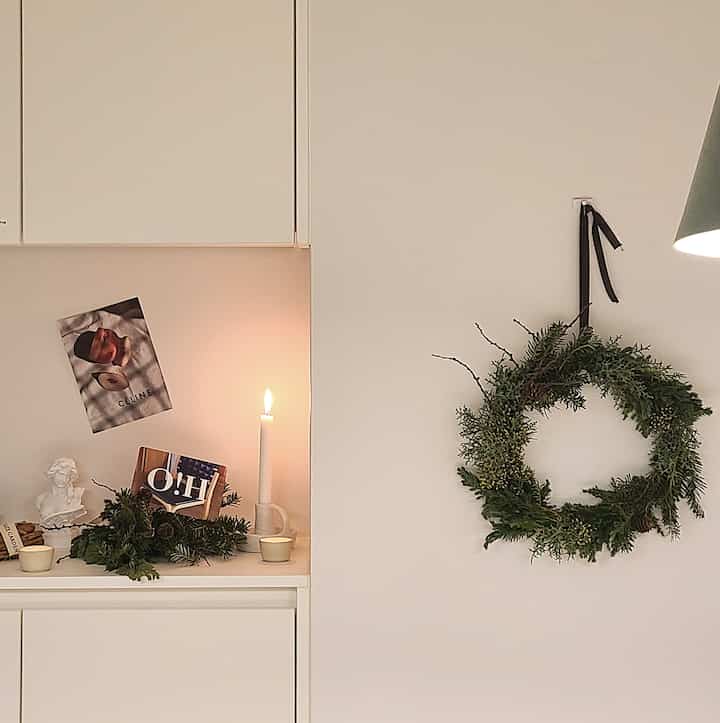 Warm white-toned dining room wall featuring a lit candle and green wreath, creating a cozy atmosphere