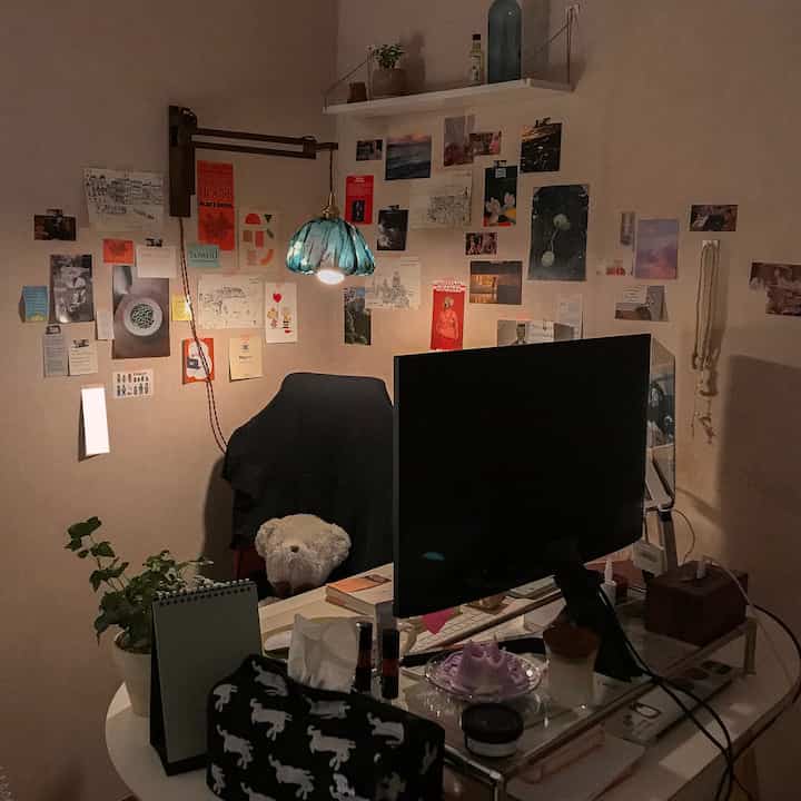 ブラウンの壁とヴィンテージ照明がある、デスクとコンピューターが配置された居心地の良いホームオフィス空間