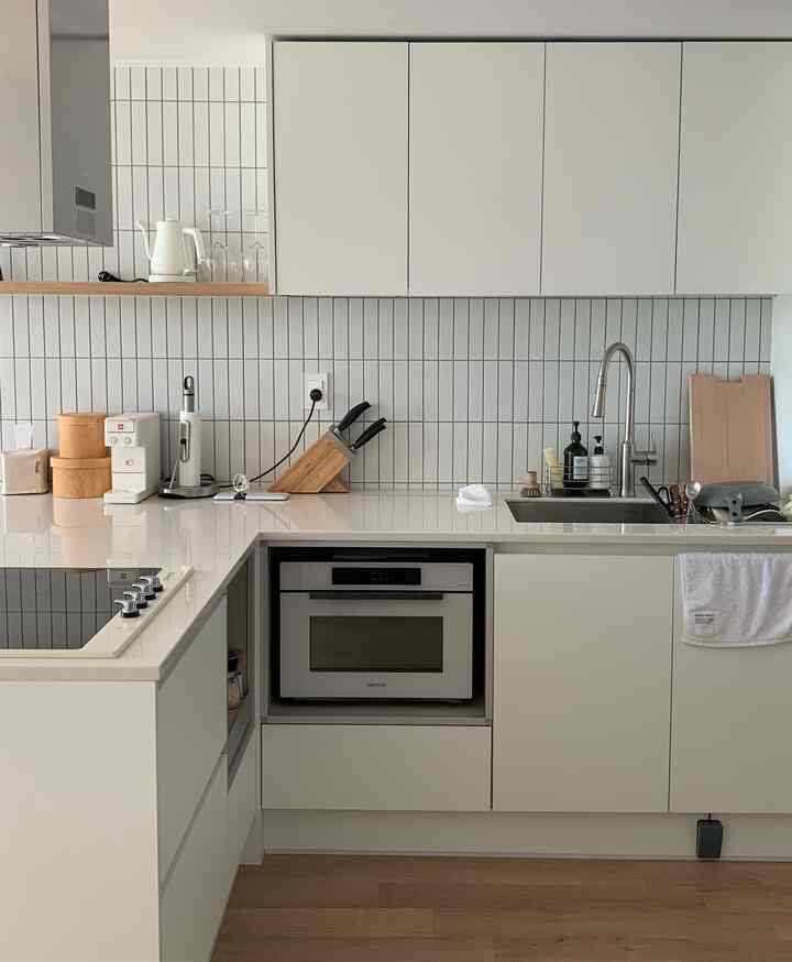 A modern kitchen in white and wood tones, featuring cooking utensils and an electric kettle in a cozy setting