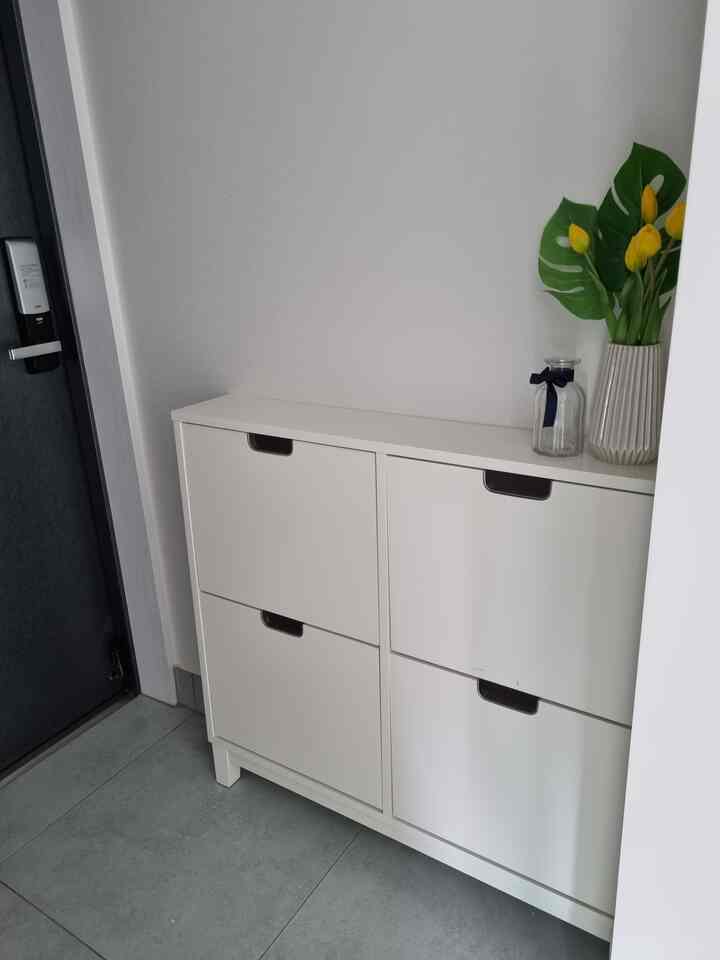 Narrow entrance in white and charcoal tones featuring IKEA shoe cabinet and decorative vases with a tidy atmosphere