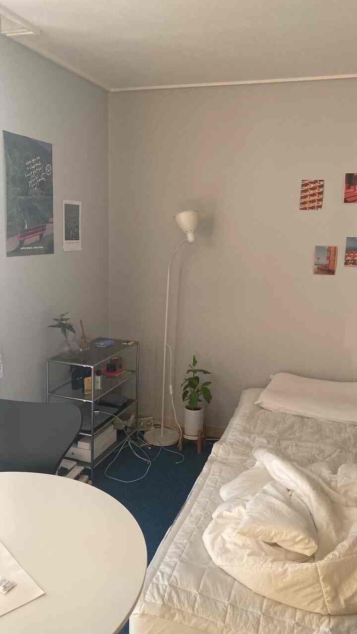 ホワイトとブルーのトーンが印象的な小さな寝室、シンプルな家具と照明が配置された落ち着いた雰囲気のインテリア