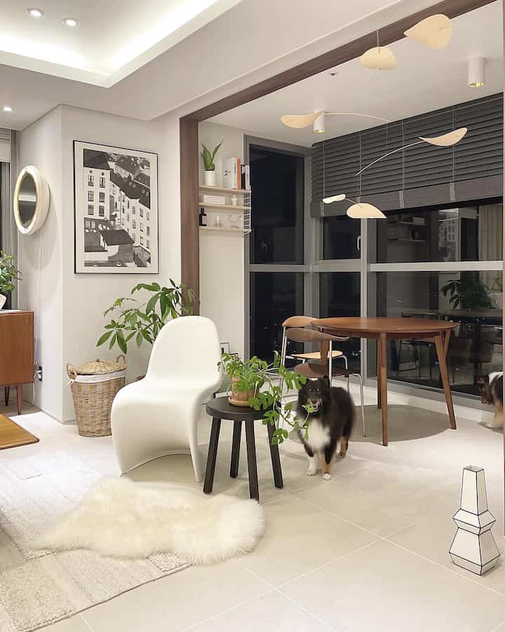 白と木目調のリビング、ミッドセンチュリーモダンのダイニングテーブルと犬がいる雰囲気のある空間