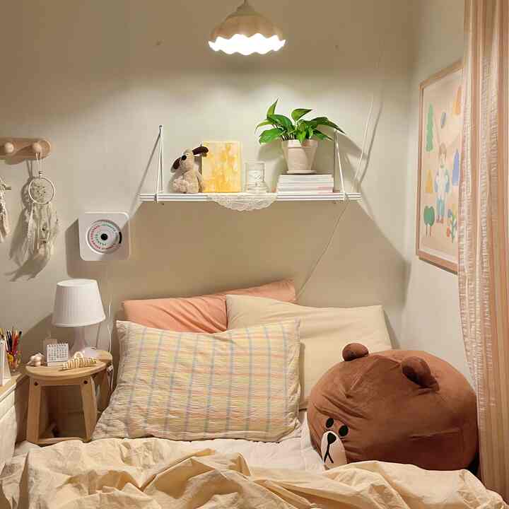 Cozy beige and white-toned bedroom featuring cushions, character plush, and charming decor on bedding and shelf
