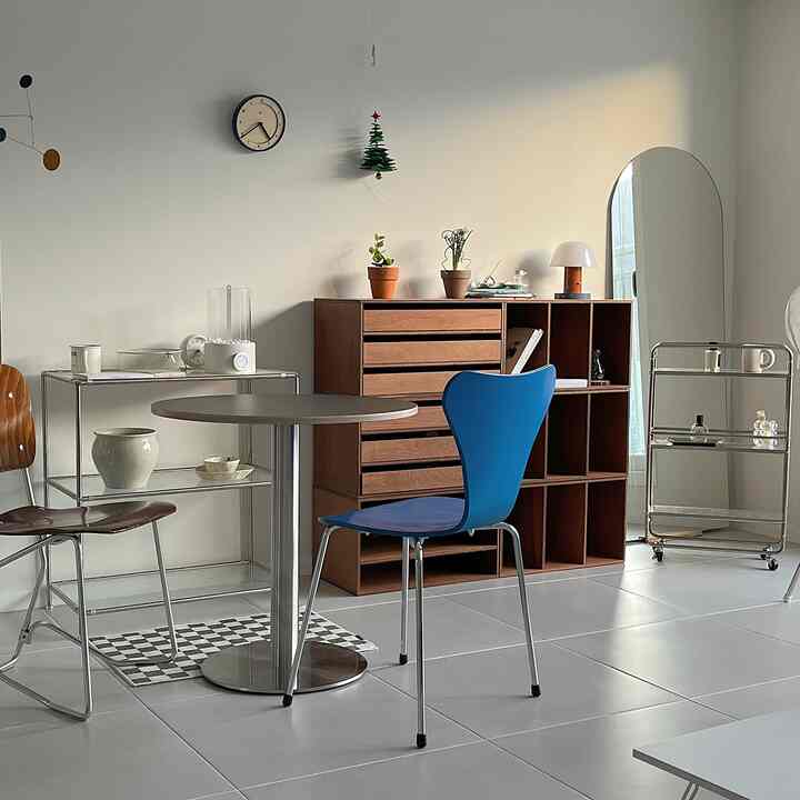 白い壁と木目調のモジュール家具が調和するリビング、ミッドセンチュリーモダンスタイルのダイニングテーブルと椅子が配置されたシンプルモダンな空間