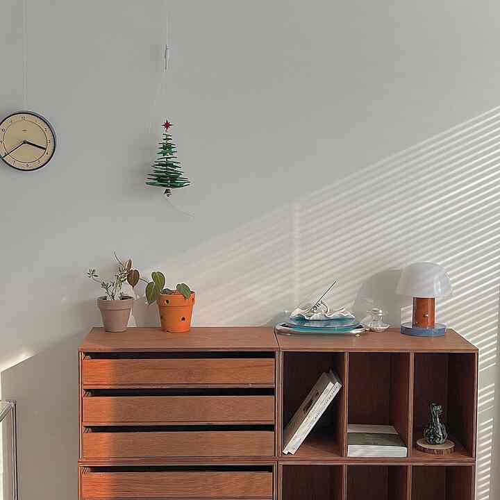 白い壁と木目調の棚があるナチュラルモダンのリビング、照明と植物で飾られた雰囲気のある空間