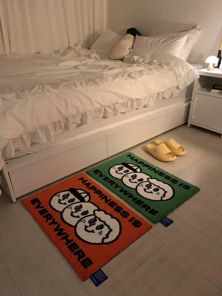 White-toned bedroom featuring a white bed, colorful rugs, and yellow slippers creating a cozy atmosphere