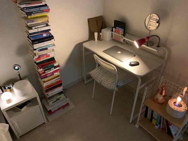 White-toned single household home office space featuring a desk and stacked books with a cozy simple modern style