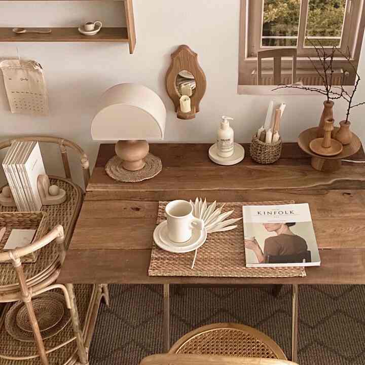 Natural tone living room with a wooden dining table, wicker chairs, and a table lamp creating a cozy atmosphere