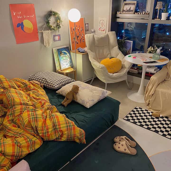 Natural-toned compact bedroom featuring a sofa bed, armchair, and floor lamp with cozy atmosphere