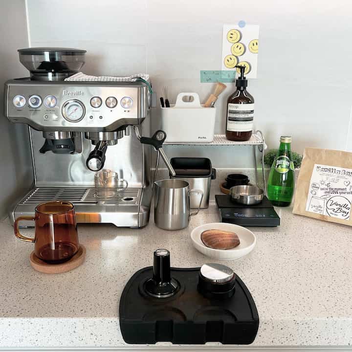 Modern kitchen home cafe featuring a stainless steel coffee machine and brown coaster with clean countertop setup