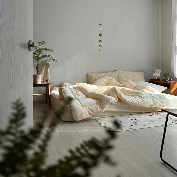 明るいアイボリーとナチュラルウッド調の寝室、柔らかな寝具と自然光が包む落ち着いた空間