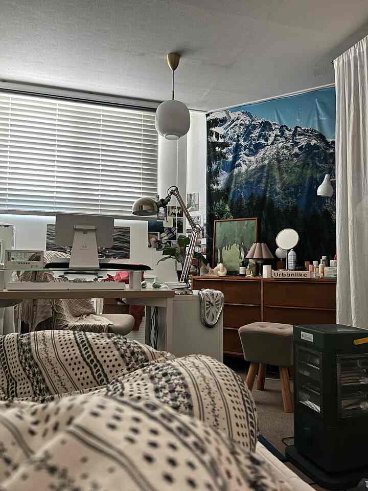 White and wood-toned bedroom featuring patterned bedding and a home office setup with a cozy vibe