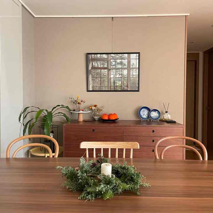 ベージュの壁紙と木目調のダイニングテーブル、椅子が配置されたナチュラルモダンなダイニングルームの雰囲気のあるインテリア