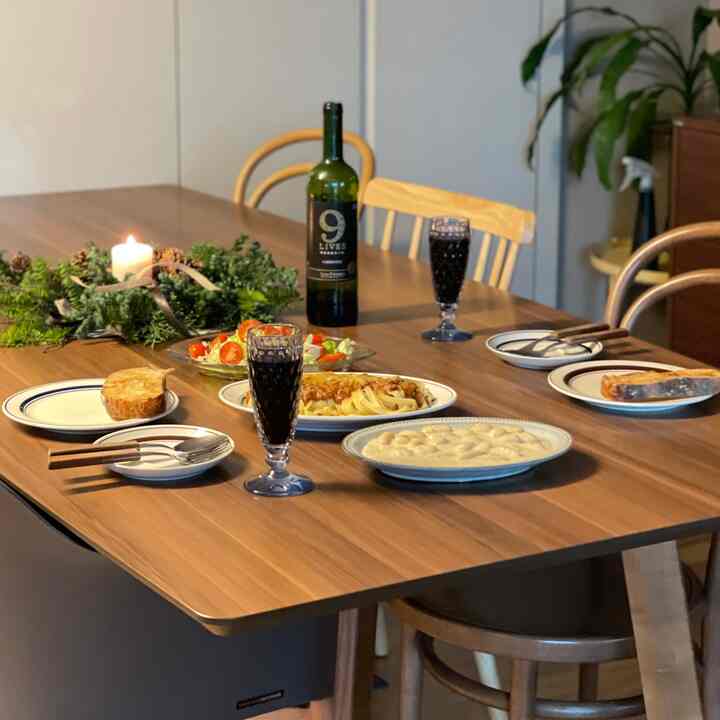 Natural brown toned dining room featuring wooden dining table with plates and wine glasses, cozy home party setting