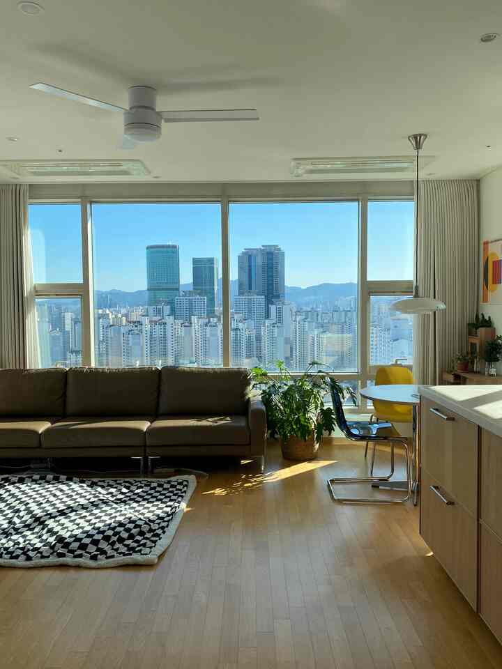 Bright natural-toned living room with large windows, sofa, and pendant light creating a clean, airy atmosphere