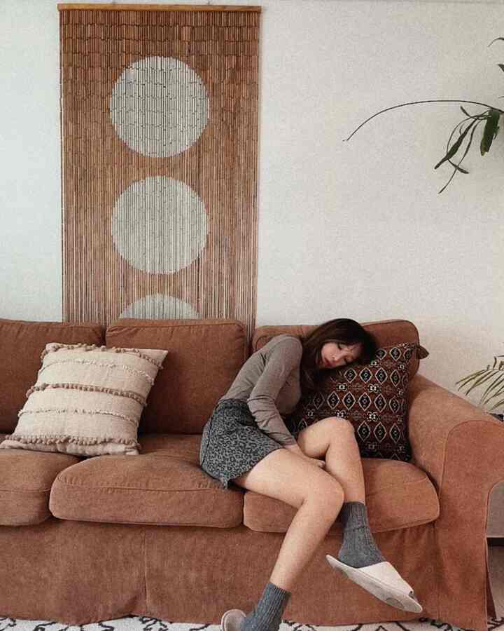 A brown-toned living room featuring a sofa with cushions and bamboo wall decoration, creating a warm natural atmosphere