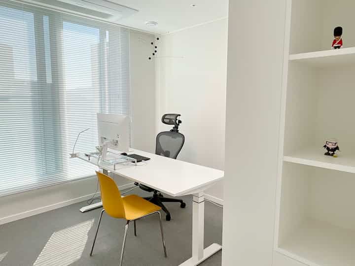 A white and gray toned home office featuring a height-adjustable desk and Aeron chair in a clean modern workspace