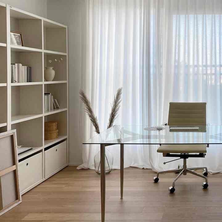 White and light brown toned study featuring a glass table and office chair in a natural and modern setting