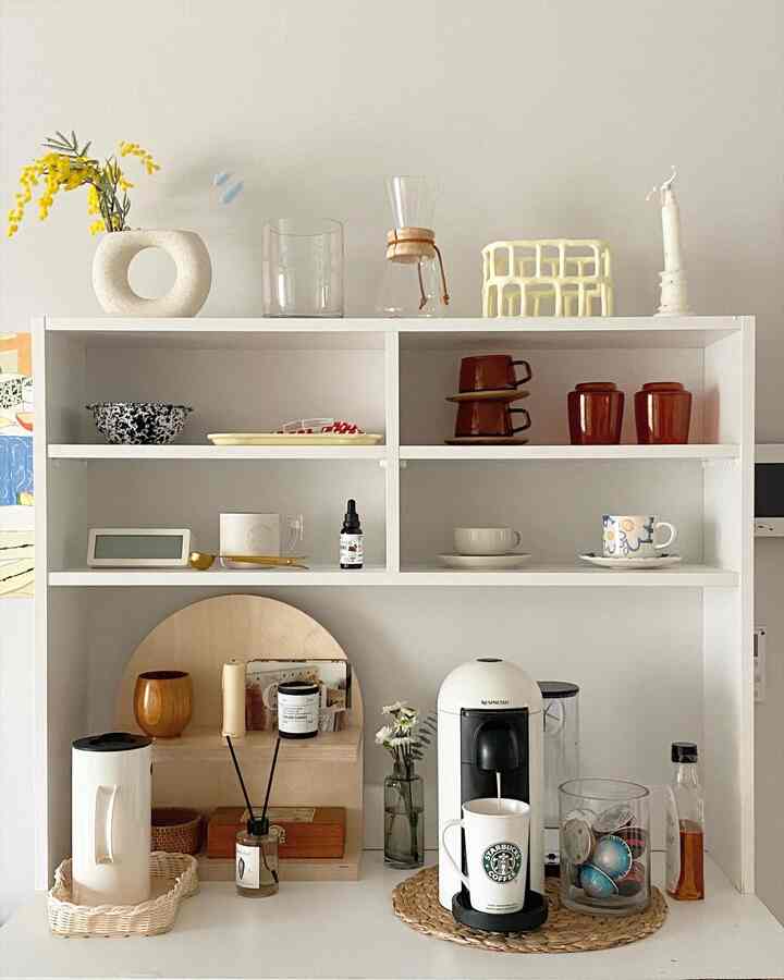 Bright white and natural tone kitchen area featuring a Nespresso coffee machine, decorative vases and trays arranged neatly creating a cozy home cafe vibe