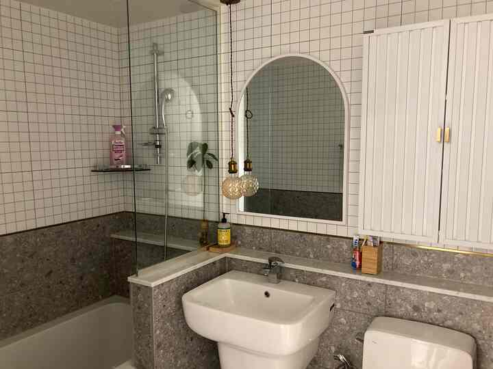 White and gray toned bathroom featuring an arched mirror, built-in bathtub, and accent lighting in a clean modern space