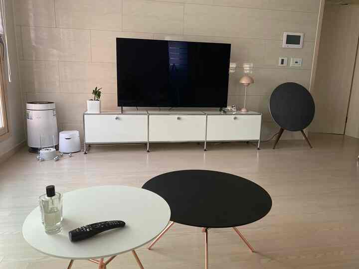 Bright white-toned living room featuring a USM TV stand and round black and white living room tables in a minimalistic space