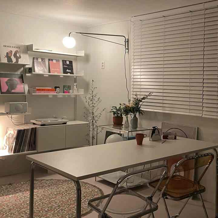 White-toned home studio music space featuring transparent chairs and wall shelves with a modern atmosphere