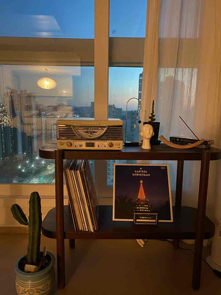 Natural wood-toned living room featuring a turntable and decorative items on a shelf with cozy atmosphere