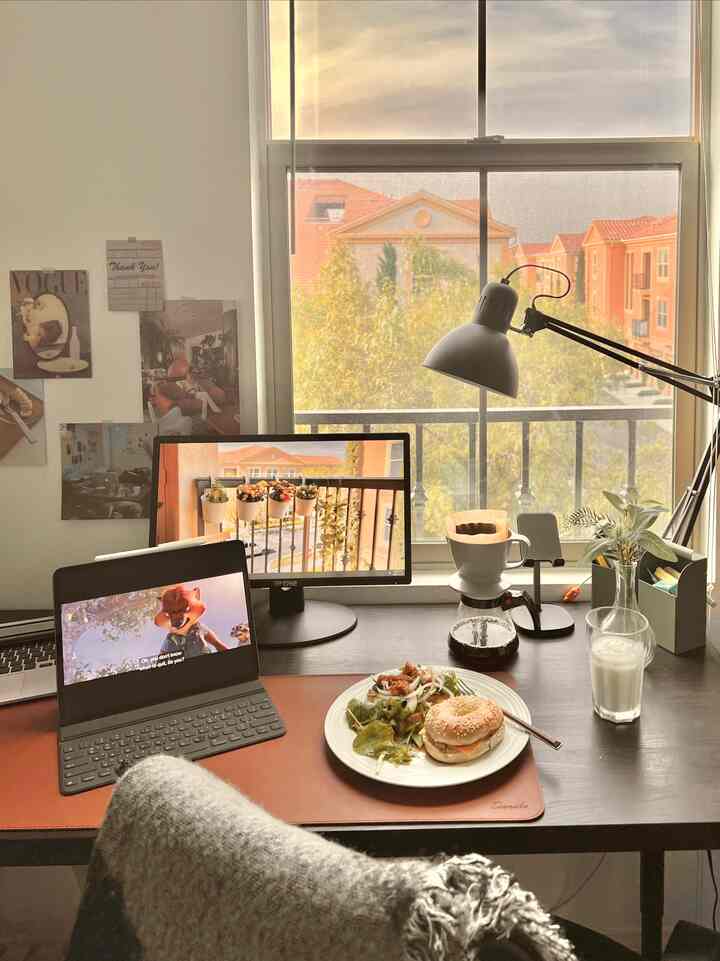 Modern home office with white walls and brown desk, featuring coffee setup and breakfast on desk, warm and cozy atmosphere