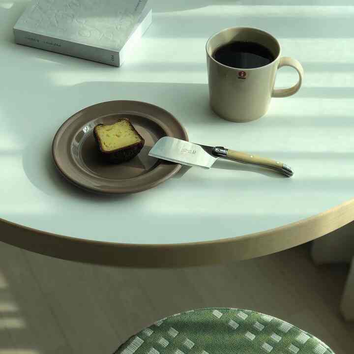 White table featuring beige plate and mug with natural light, creating a minimal home cafe setting