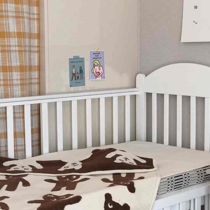 White and brown toned kids' room featuring a crib with a cute bear-patterned throw blanket, creating a cozy atmosphere