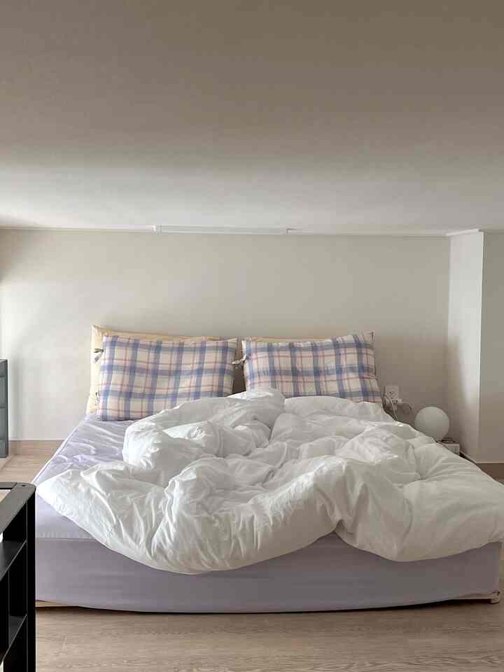 Beige-toned walls and white bedding in a studio bedroom, creating a clean and cozy atmosphere