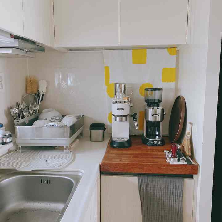 明るいホワイトと木目調のキッチン空間、コーヒーマシンと調理器具が整然と配置された雰囲気のあるおうちカフェのキッチン