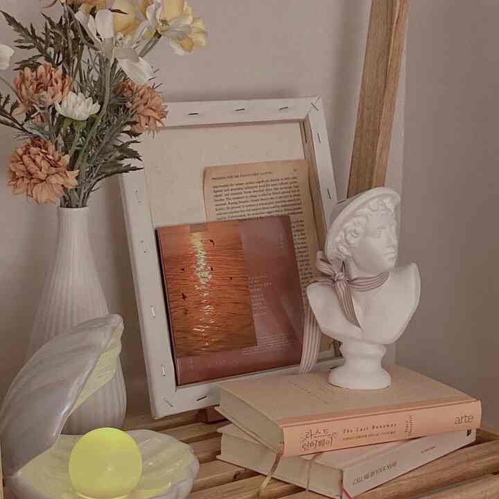 A natural-toned and white decorative display featuring a mood lamp and plaster bust objet, creating a cozy ambiance