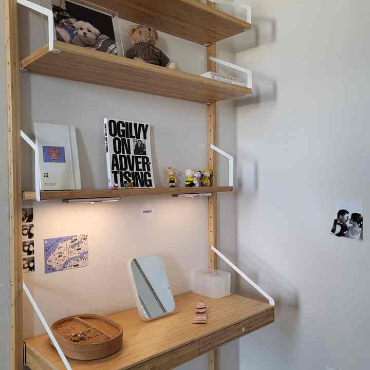 Natural wood shelves and IKEA SVALNÄS vanity with a mirror against white wall in a simple, cozy single household space