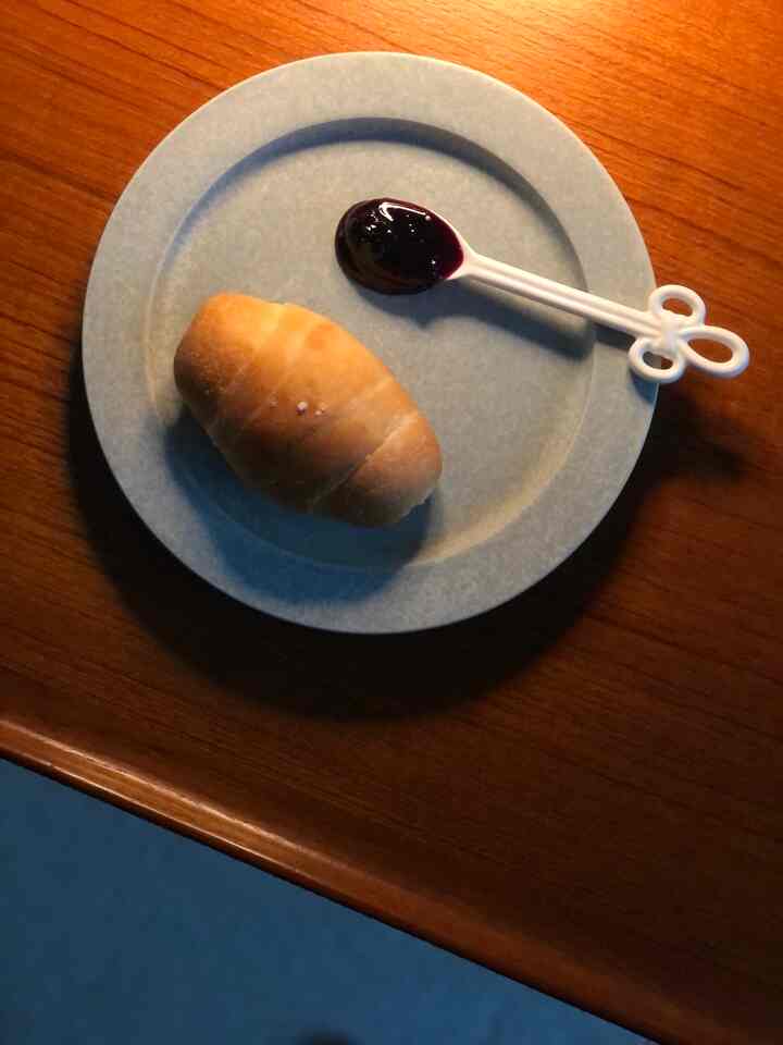 Natural and vintage home cafe setting featuring a light blue plate with salt bread and white spoon on warm wood tone table