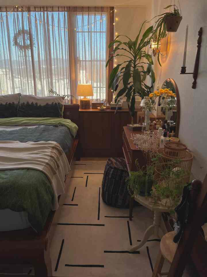 A natural color and wood tone bedroom featuring cozy curtains, natural furniture, and plants bathed in soft morning light