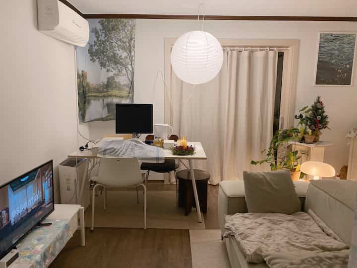 Warm beige and wood tone living room and home office featuring sofa and dining table in a cozy setting