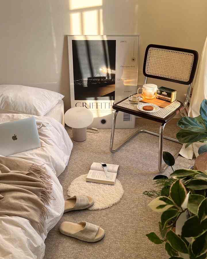 ベージュとナチュラル色調の寝室、ラタンチェアと大型の額縁が配置された雰囲気のあるインテリア