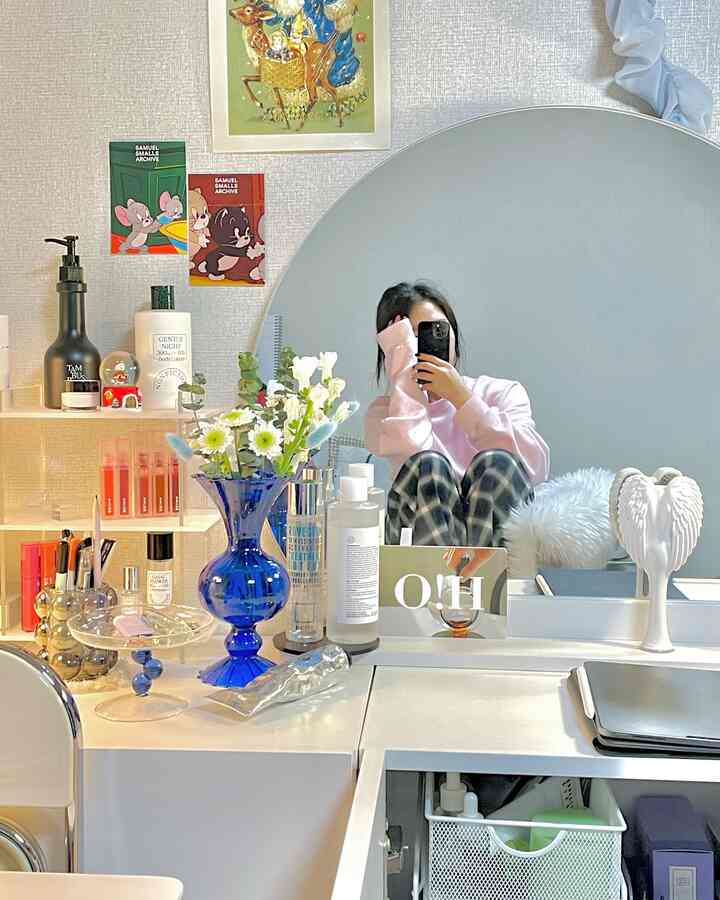 ホワイトとナチュラルカラーの化粧台空間、大きな丸い鏡と青い花瓶がアクセントの一人暮らし向けの居心地の良い部屋