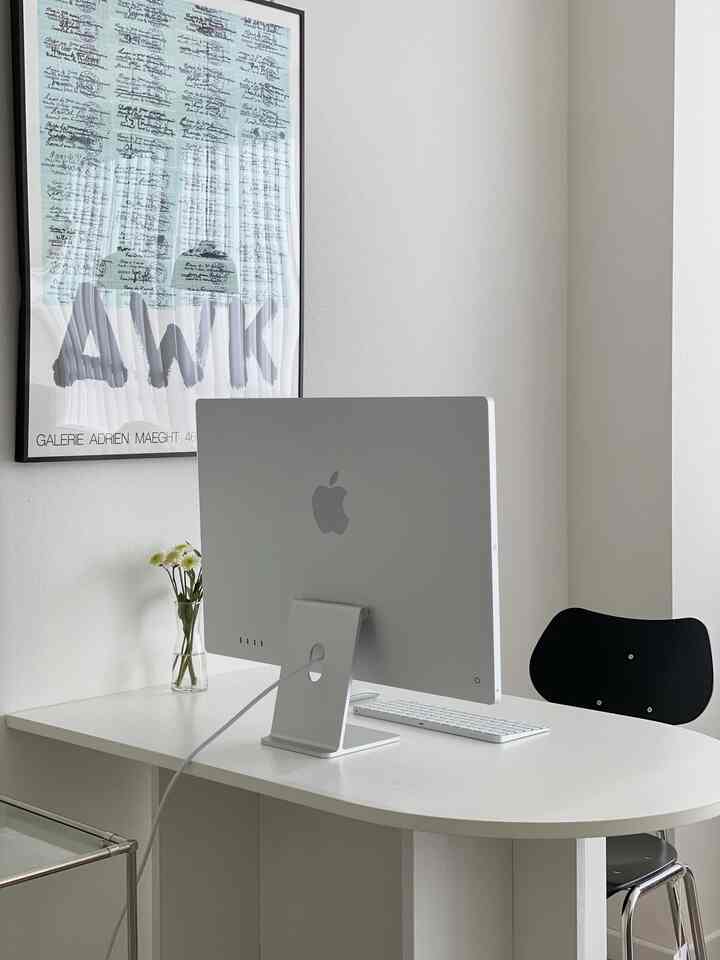 ホワイトトーンのホームオフィス、白いデスクとiMac、黒い椅子が配置されたミニマルで清潔感のあるインテリア