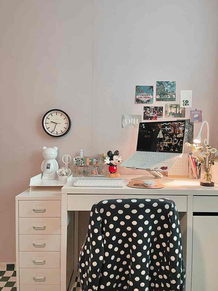 Soft beige wall home office featuring white desk, drawer, wall clock, and vase with a neat, cozy atmosphere