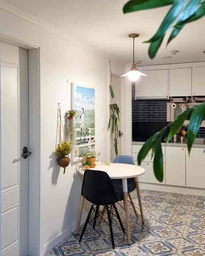 白い壁と青い柄のタイル床のキッチン、円形テーブルと椅子が配置され、落ち着いたモダンな雰囲気の空間