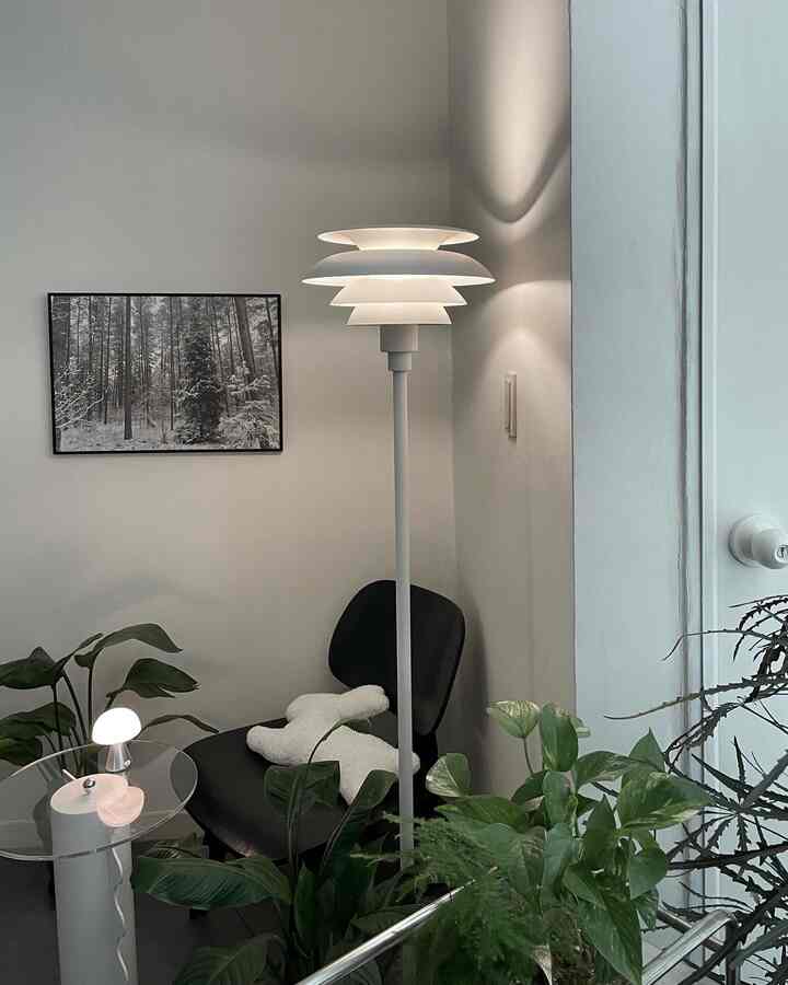 White-toned walls and plants in a modern living room, featuring a floor lamp and armchair with cozy atmosphere