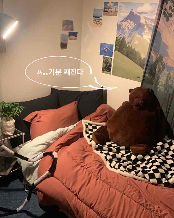 Cozy bedroom with warm brown and orange tones, featuring a plush bed, large bear plushie, and checkered throw blanket