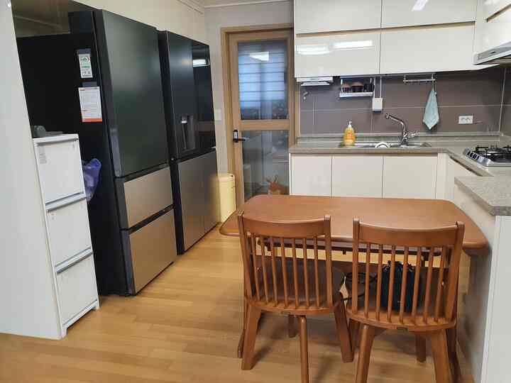 原木と濃いグリーンが暖かいキッチン、さわやかな黄色のごみ箱はポイント