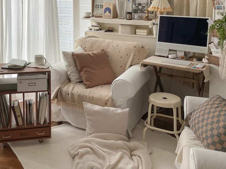 White and brown toned living room featuring white armchairs, stool, and computer desk creating a cozy home office space
