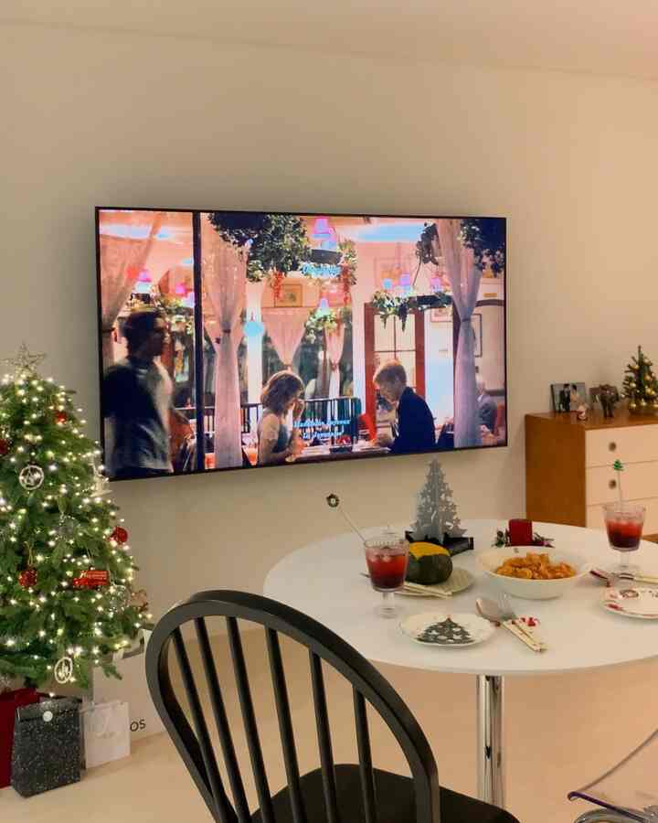 ホワイトトーンのリビング、円形テーブルとクリスマスツリーの装飾、テレビが配置された雰囲気あるホームパーティースペース