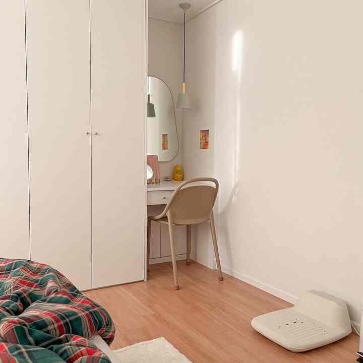 ナチュラルカラーと木目調の6畳寝室、コーナーにアーチ型ミラーと化粧台が配置されたシンプルモダンなインテリア