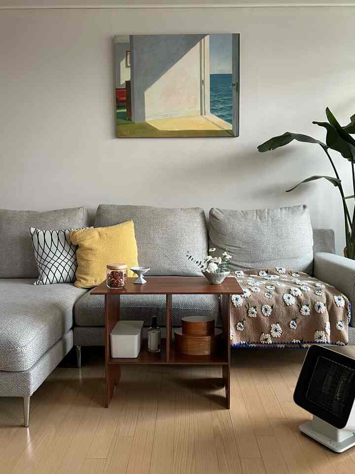 Wood-toned living room with gray modular sofa and wooden coffee table, featuring blanket and cushions creating a cozy atmosphere
